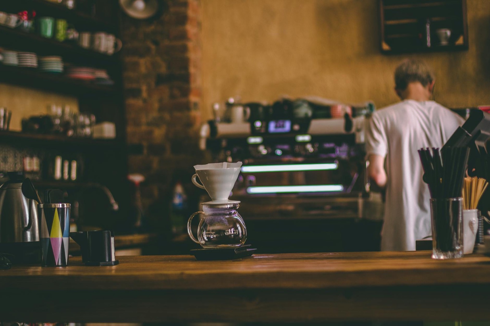 Dripper V60 na barze kawiarni, w tle barista przy ekspresie